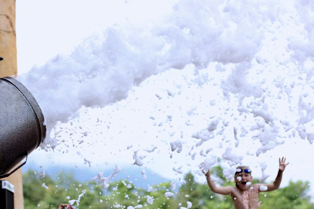 Outdoor view of foam machine. Group of people having fun, enjoying at a foam party in aquapark.